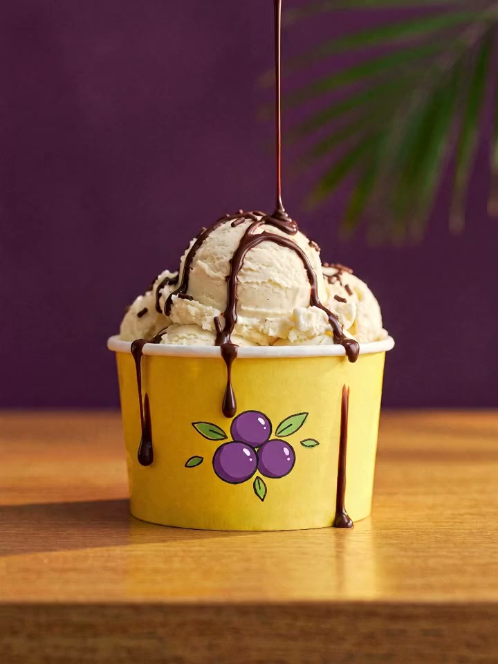 Pote amarelo de sorvete com cobertura de chocolate escorrendo